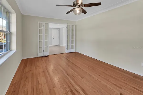 a view of empty room with wooden floor and fan
