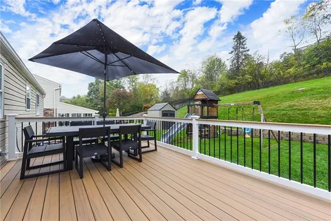 a view of a roof deck with table and chairs under an umbrella with wooden floor