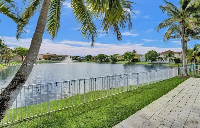 a view of a lake with a big yard and palm trees