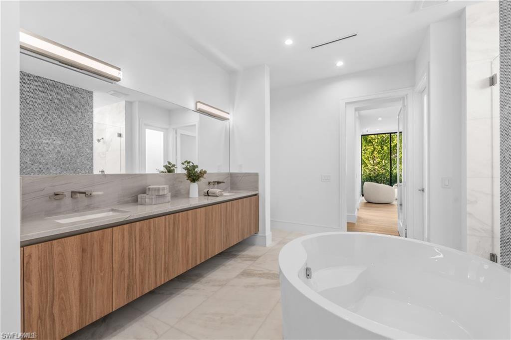 1800 Crayton Road Naples, FL 34102 - Photo 18 of 32 Full bathroom with a shower stall, double vanity, recessed lighting, a freestanding tub, and light marble finish flooring