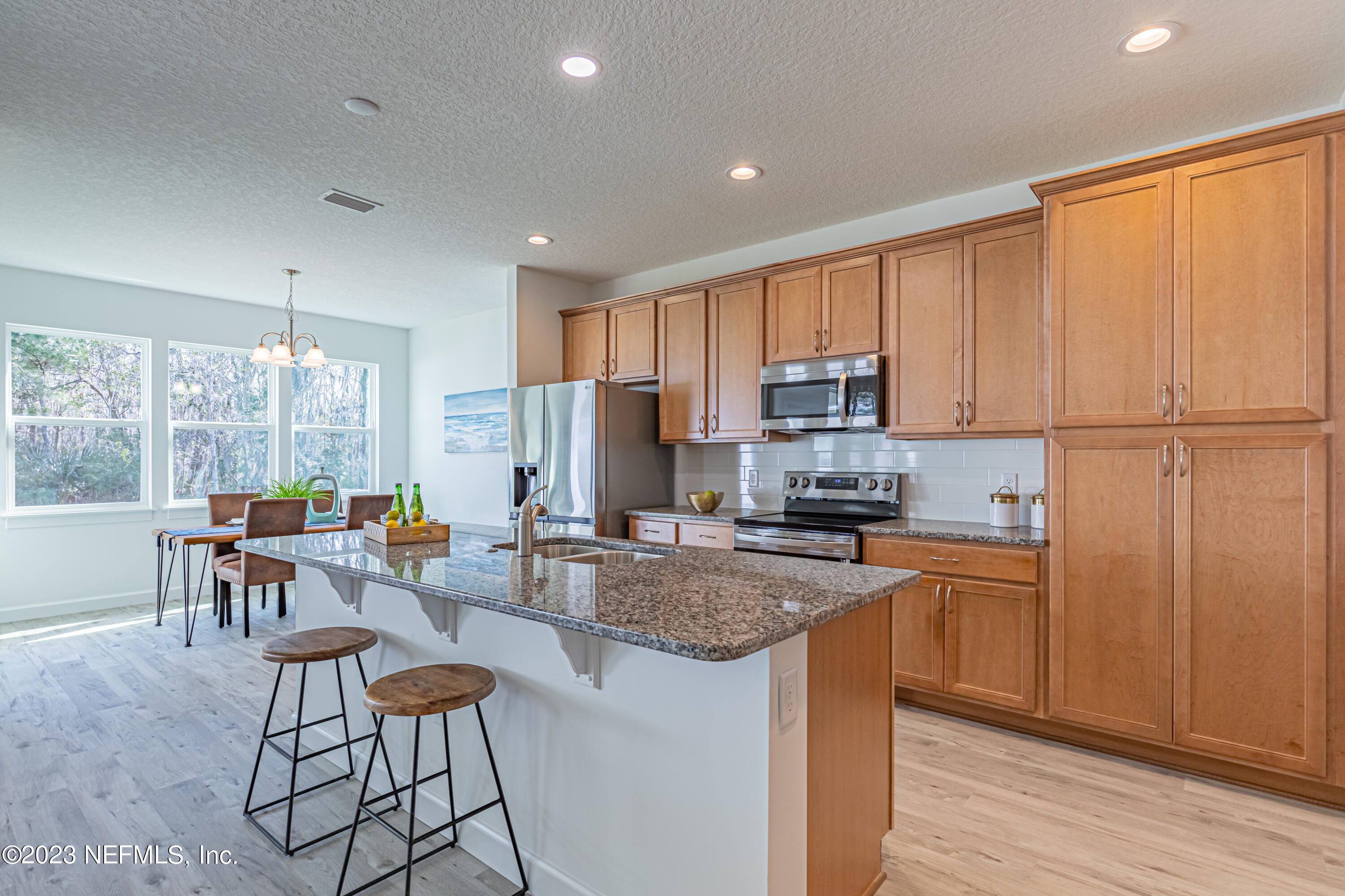 3093 Orange Picker Road Jacksonville, FL 32223 - Photo 13 of 39 a kitchen with a refrigerator a stove a dining table and chairs with wooden floor