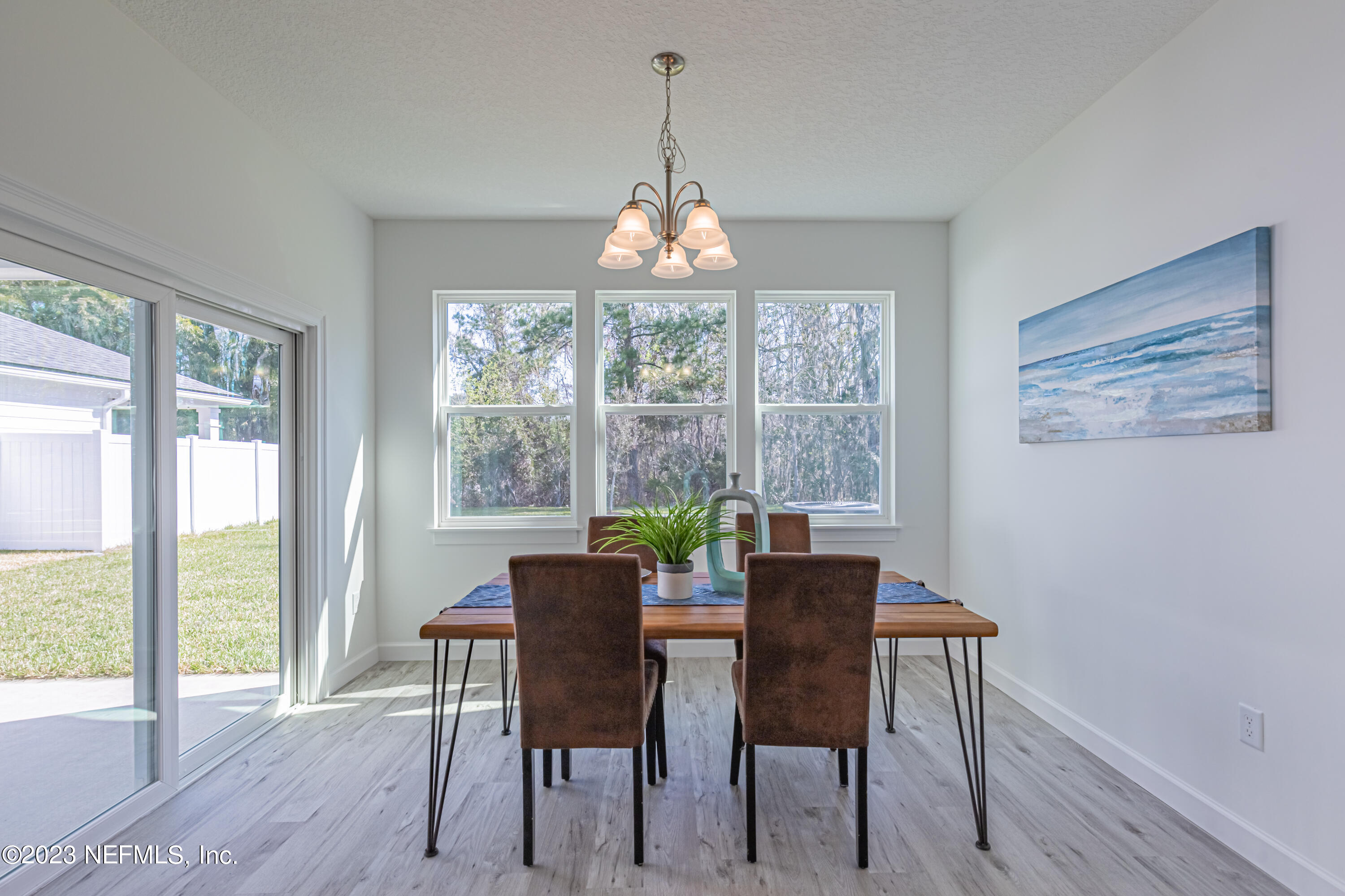 3093 Orange Picker Road Jacksonville, FL 32223 - Photo 18 of 39 a dining room with wooden floor a chandelier a glass table and chairs