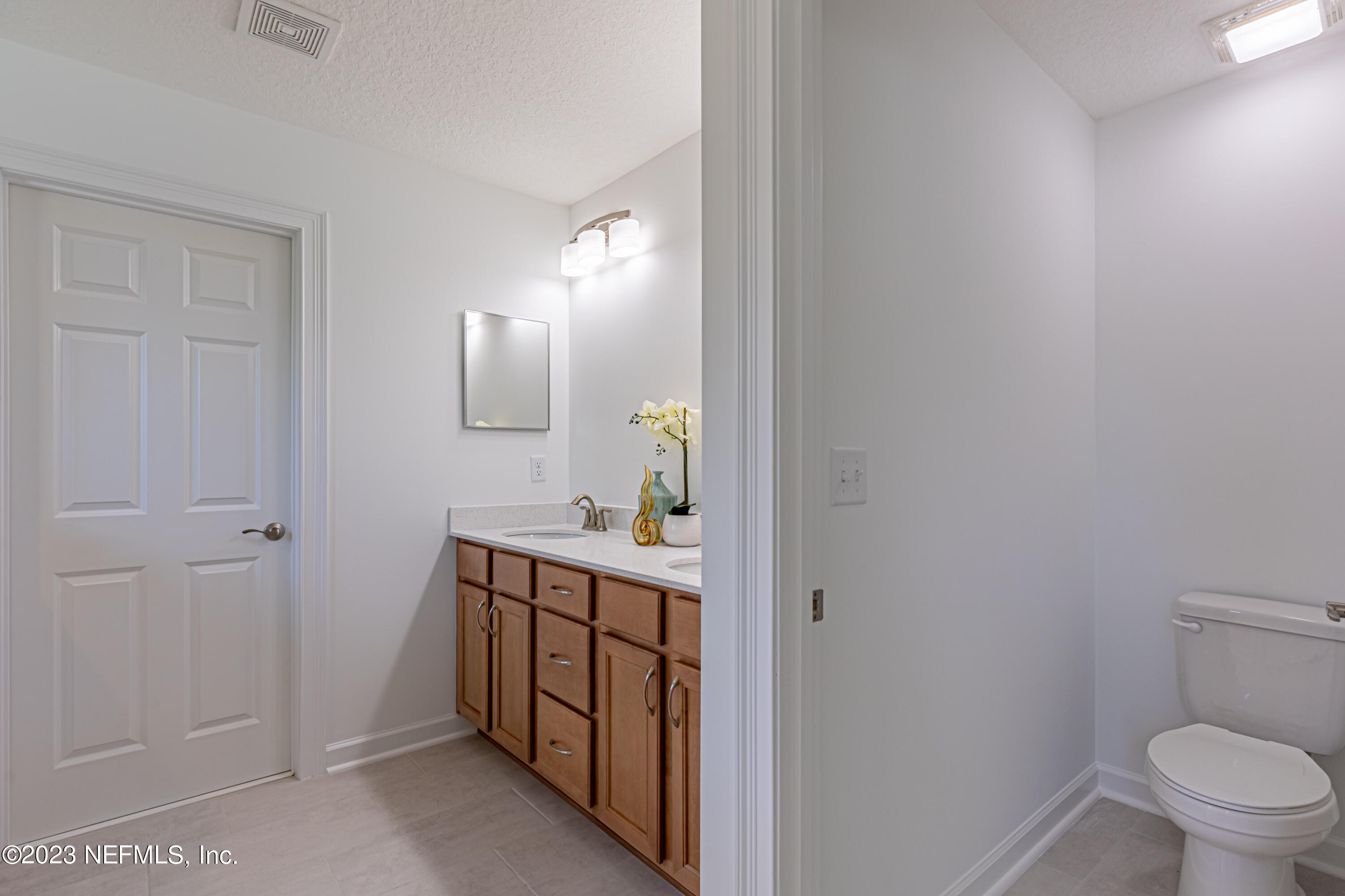 3093 Orange Picker Road Jacksonville, FL 32223 - Photo 26 of 39 a bathroom with a toilet a sink a vanity and mirror