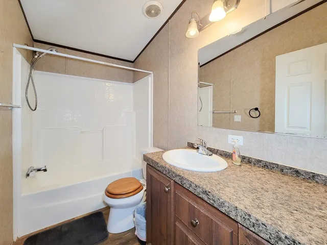 a bathroom with a granite countertop sink a mirror and a shower