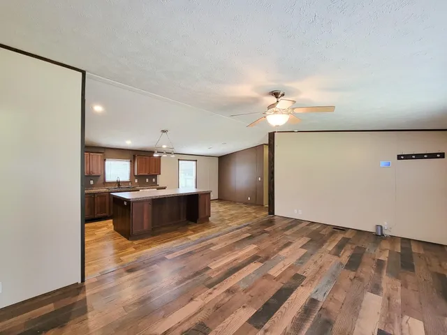 a view of an empty room with windows and chandelier fan