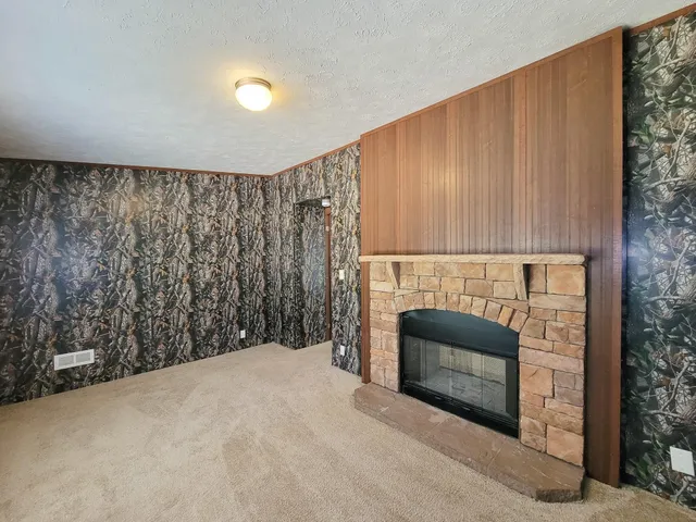 a view of an empty room with a fireplace and a window