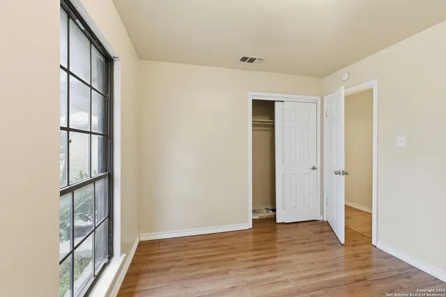a view of empty room with wooden floor and window