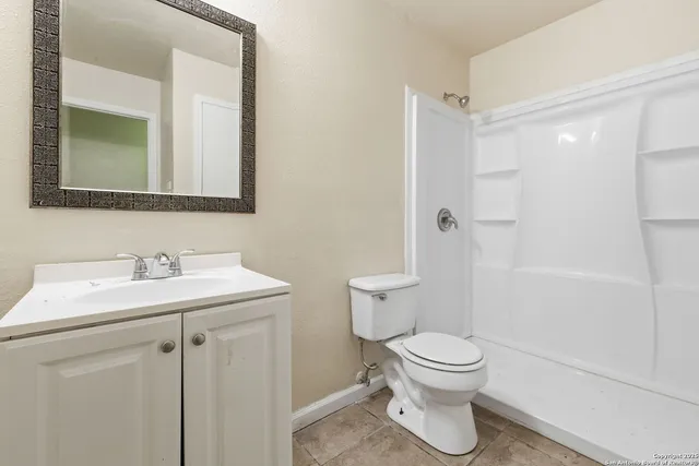 a bathroom with a toilet sink a mirror and shower