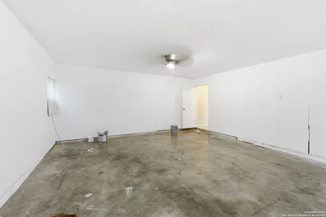 an empty room with a chandelier fan and windows