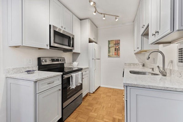 a kitchen with stainless steel appliances granite countertop a sink and a stove top oven with white countertops