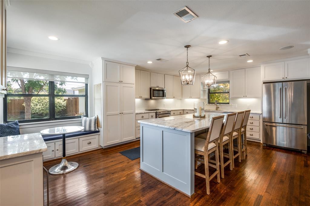 a kitchen with stainless steel appliances granite countertop a table chairs refrigerator and wooden floor