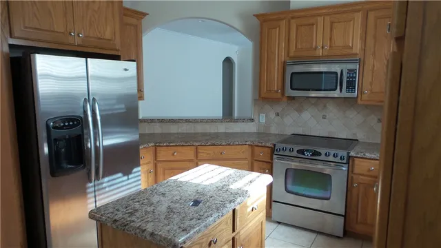 a kitchen with granite countertop a sink stove and refrigerator