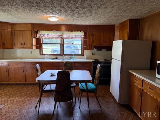 a kitchen with stainless steel appliances dining table chairs and a refrigerator