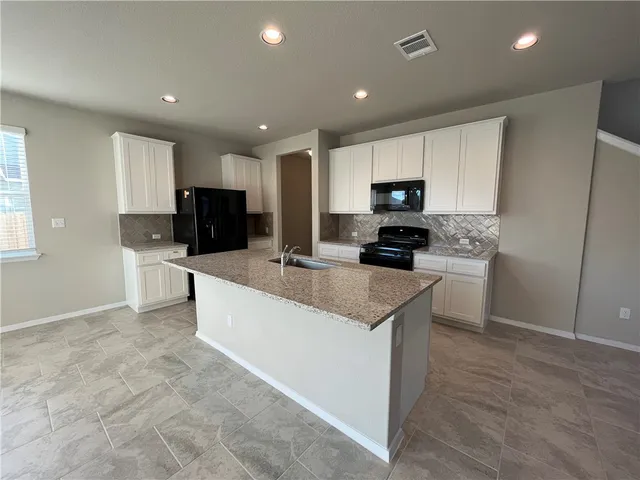 a kitchen with granite countertop a refrigerator and a stove top oven