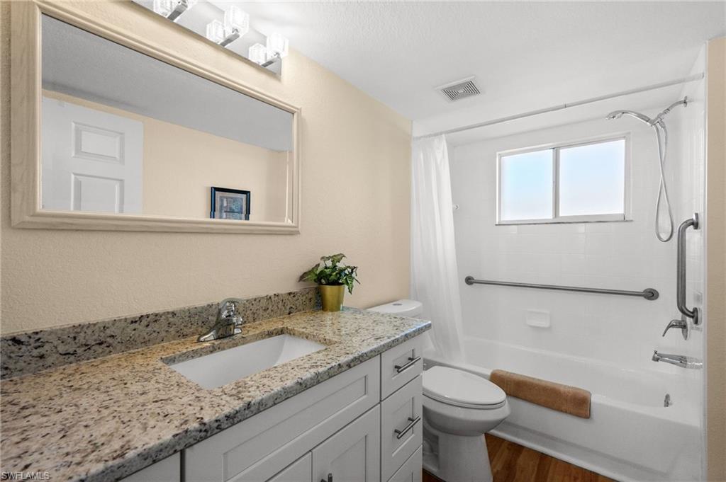 8264 Key Royal Circle, Unit 812 Naples, FL 34119 - Photo 20 of 21 Full bathroom with vanity, shower / tub combo with curtain, dark wood-style flooring, and a textured wall
