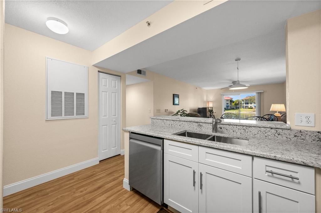 8264 Key Royal Circle, Unit 812 Naples, FL 34119 - Photo 4 of 21 Kitchen with a peninsula, dishwasher, light stone countertops, white cabinetry, and ceiling fan