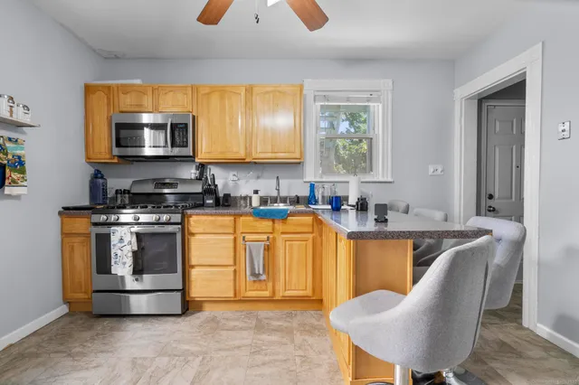 a kitchen with stainless steel appliances granite countertop a stove top oven a sink a dining table and chairs