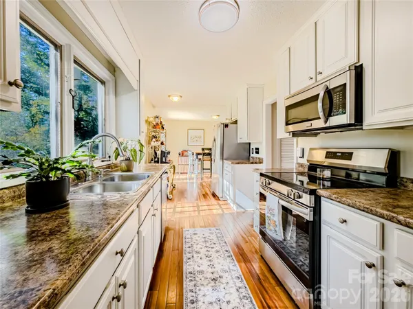 a kitchen with stainless steel appliances granite countertop a stove a sink and a microwave