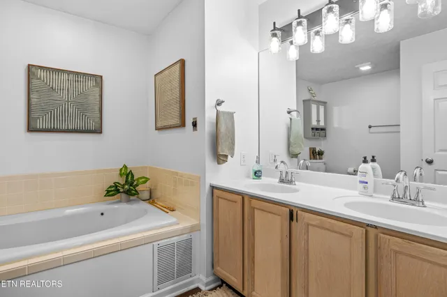 a bathroom with a double vanity sink mirror and bathtub