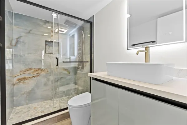 a bathroom with a sink a toilet a mirror and shower