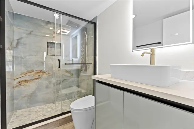 a bathroom with a sink a toilet a mirror and shower