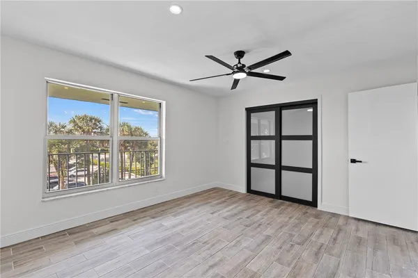 a view of empty room with wooden floor and fan