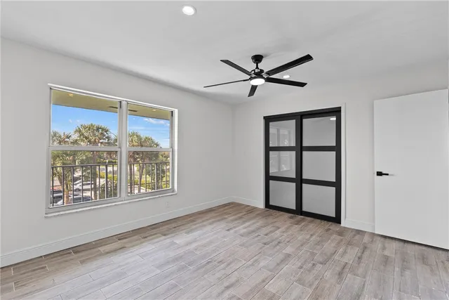 a view of empty room with wooden floor and fan