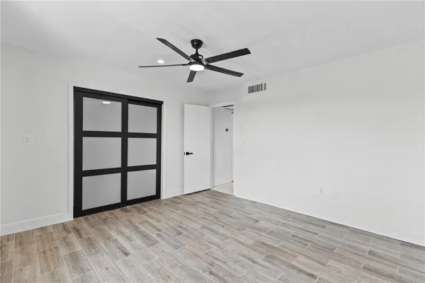 a view of empty room with wooden floor and fan