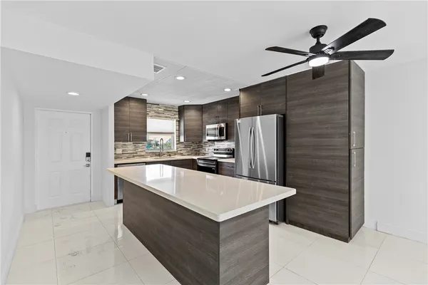 a large kitchen with stainless steel appliances kitchen island a refrigerator and a sink