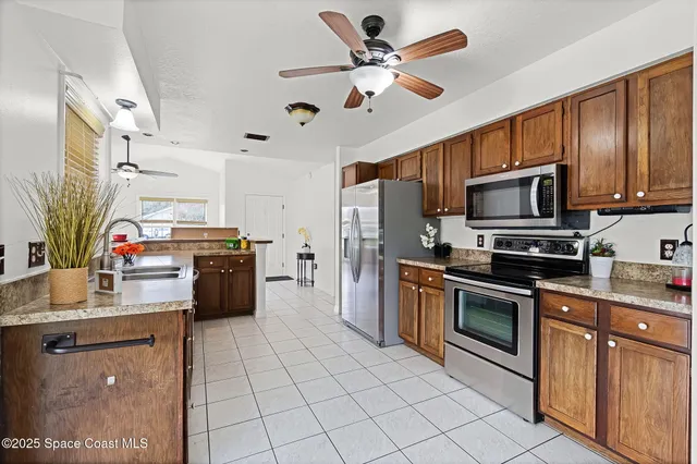 a kitchen with granite countertop a refrigerator a sink dishwasher stove top oven and cabinets