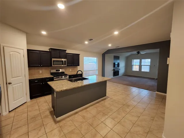 a kitchen with granite countertop a sink a stove top oven a refrigerator and a sink