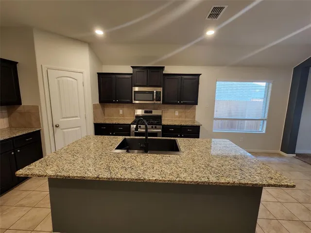 a kitchen with stainless steel appliances granite countertop a refrigerator a stove a sink and a microwave