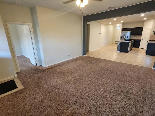 an empty room with a chandelier fan and windows