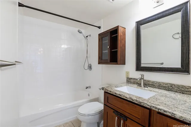 a bathroom with a granite countertop sink mirror vanity and toilet