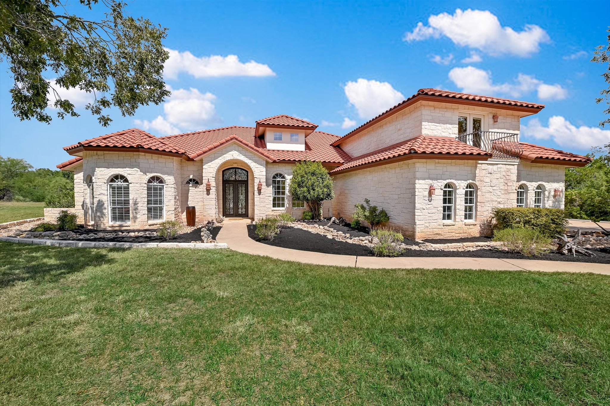 Mediterranean / spanish-style home featuring stone siding, a front lawn, and french doors