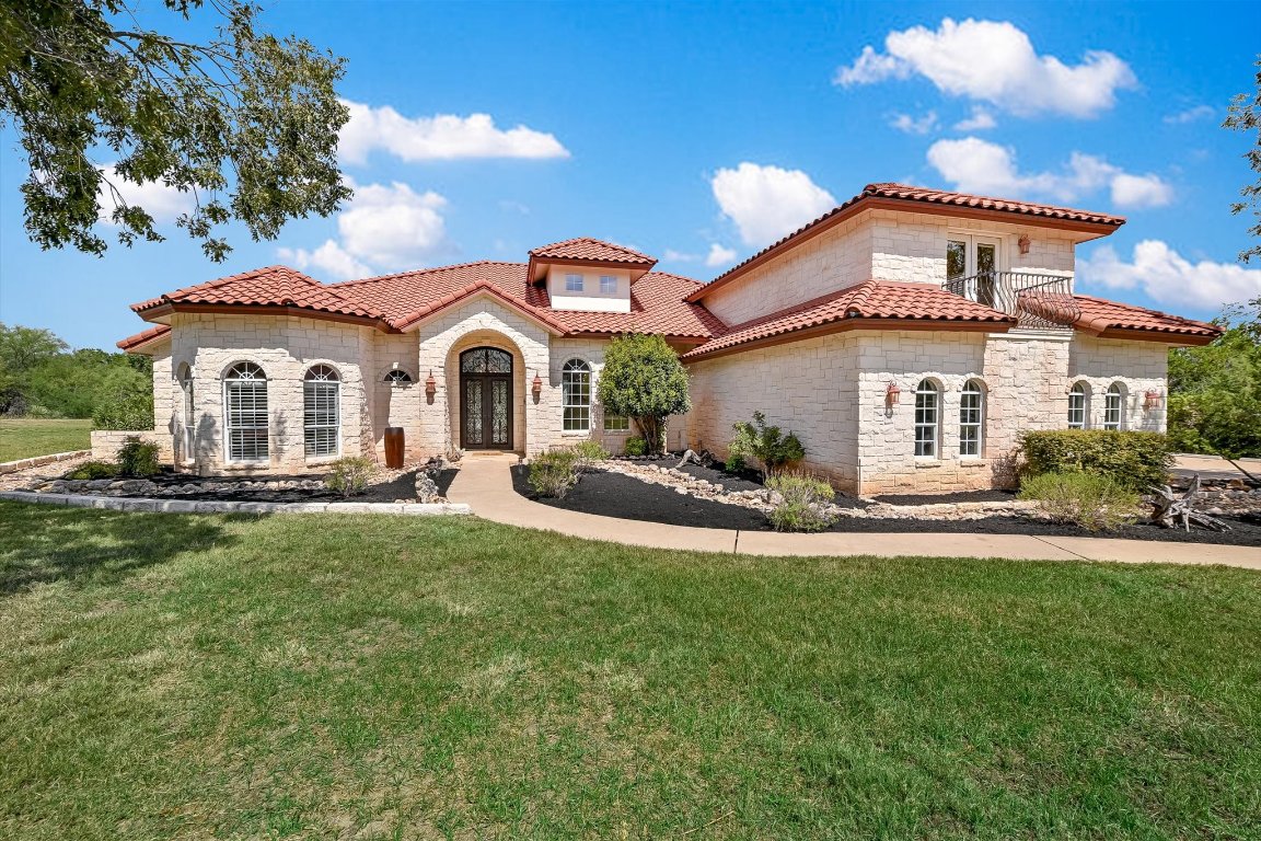 Mediterranean / spanish-style home featuring stone siding, a front lawn, and french doors