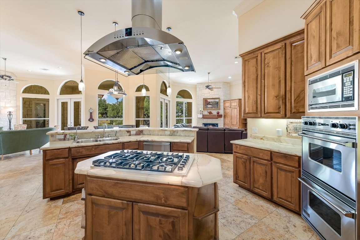 1001 Wesley Ridge Drive Spicewood, TX 78669 - Photo 35 of 35 Kitchen featuring open floor plan, brown cabinets, a ceiling fan, stainless steel appliances, and island exhaust hood