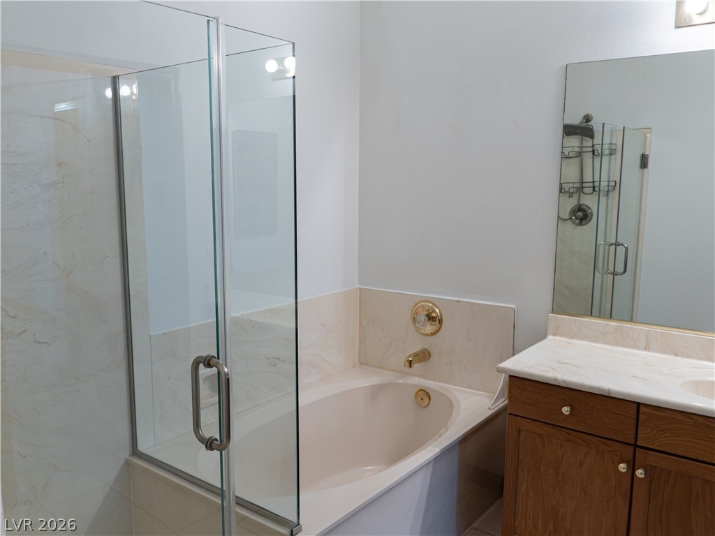 1466 Orange Jubilee Road Henderson, NV 89014 - Photo 11 of 15 A well-appointed bathroom features a glass-enclosed shower alongside a deep soaking tub and a functional vanity.