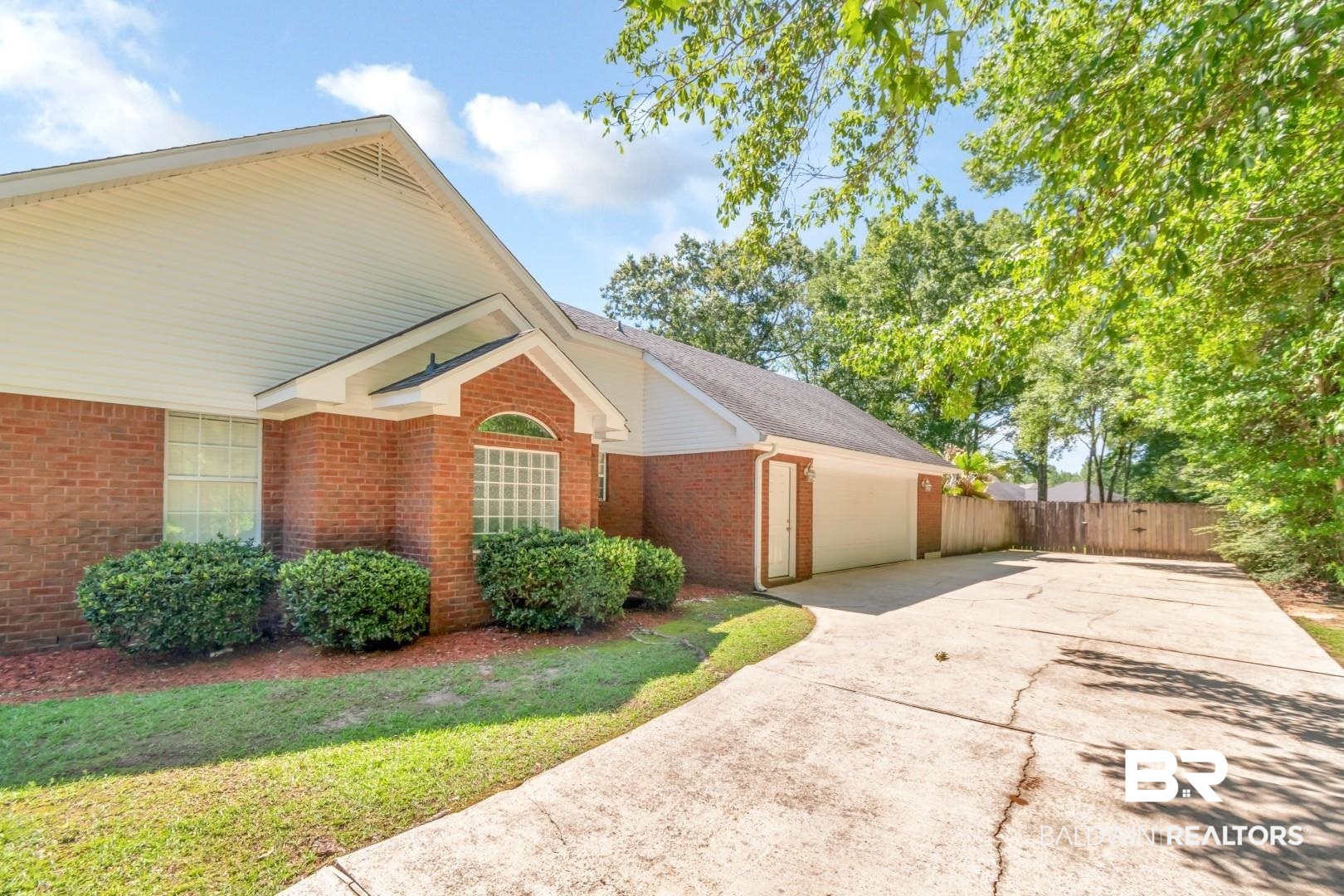 10691 Hunters Ridge Drive Mobile, AL 36695 - Photo 26 of 37 Brick exterior residence featuring a concrete driveway, attached two-car garage, manicured shrubbery, and a wood privacy fence
