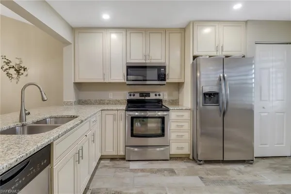 a kitchen with a refrigerator sink and cabinets