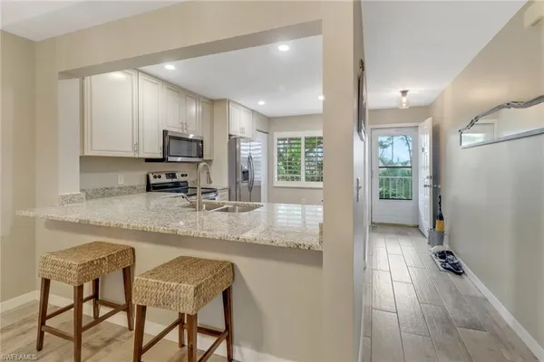 a kitchen with kitchen island granite countertop a stove a sink and a refrigerator with wooden floor