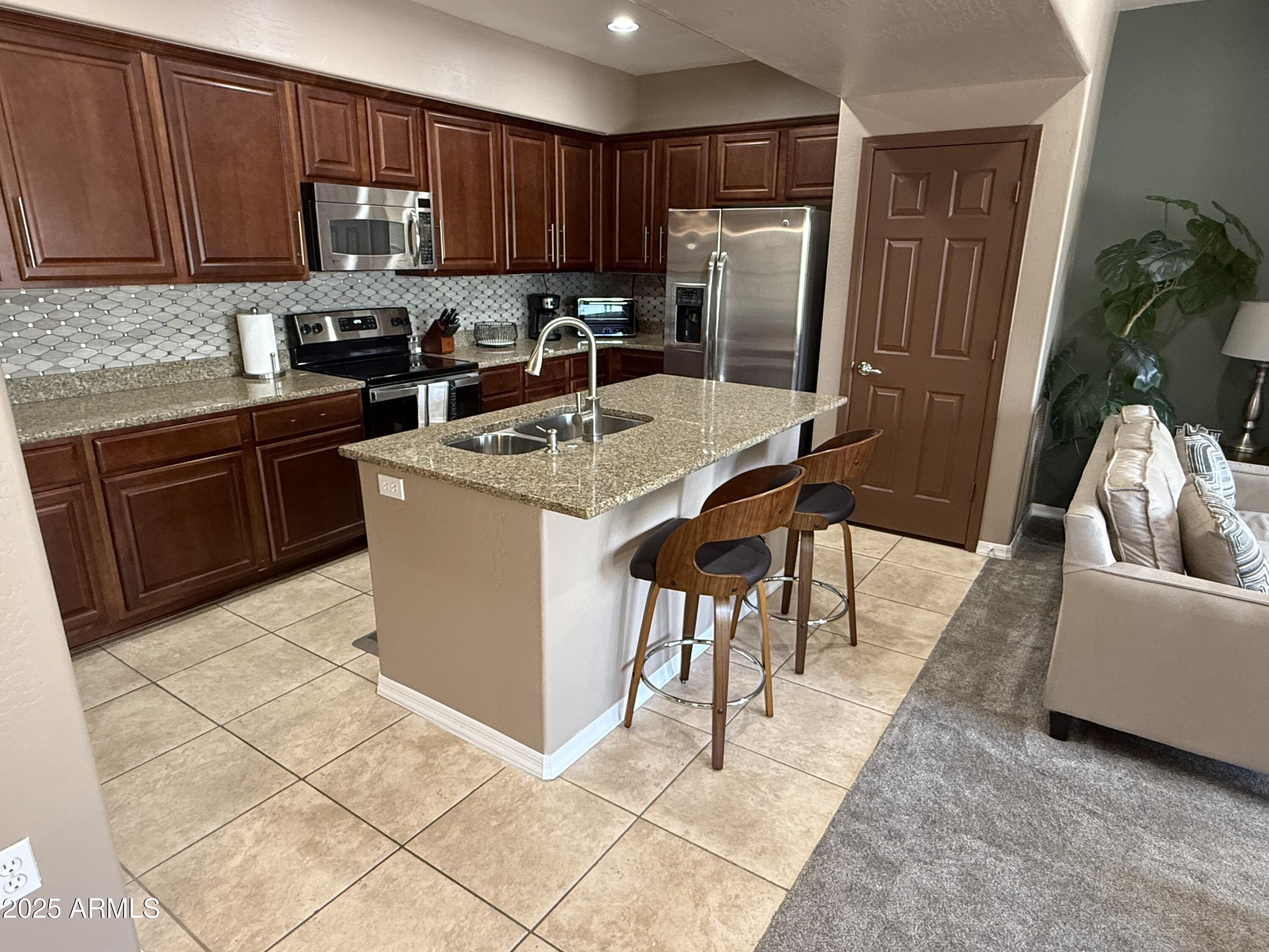 3935 East Rough Rider Road, Unit 1014 Phoenix, AZ 85050 - Photo 5 of 40 a kitchen with stainless steel appliances granite countertop a refrigerator a stove a sink a microwave a dining table and chairs
