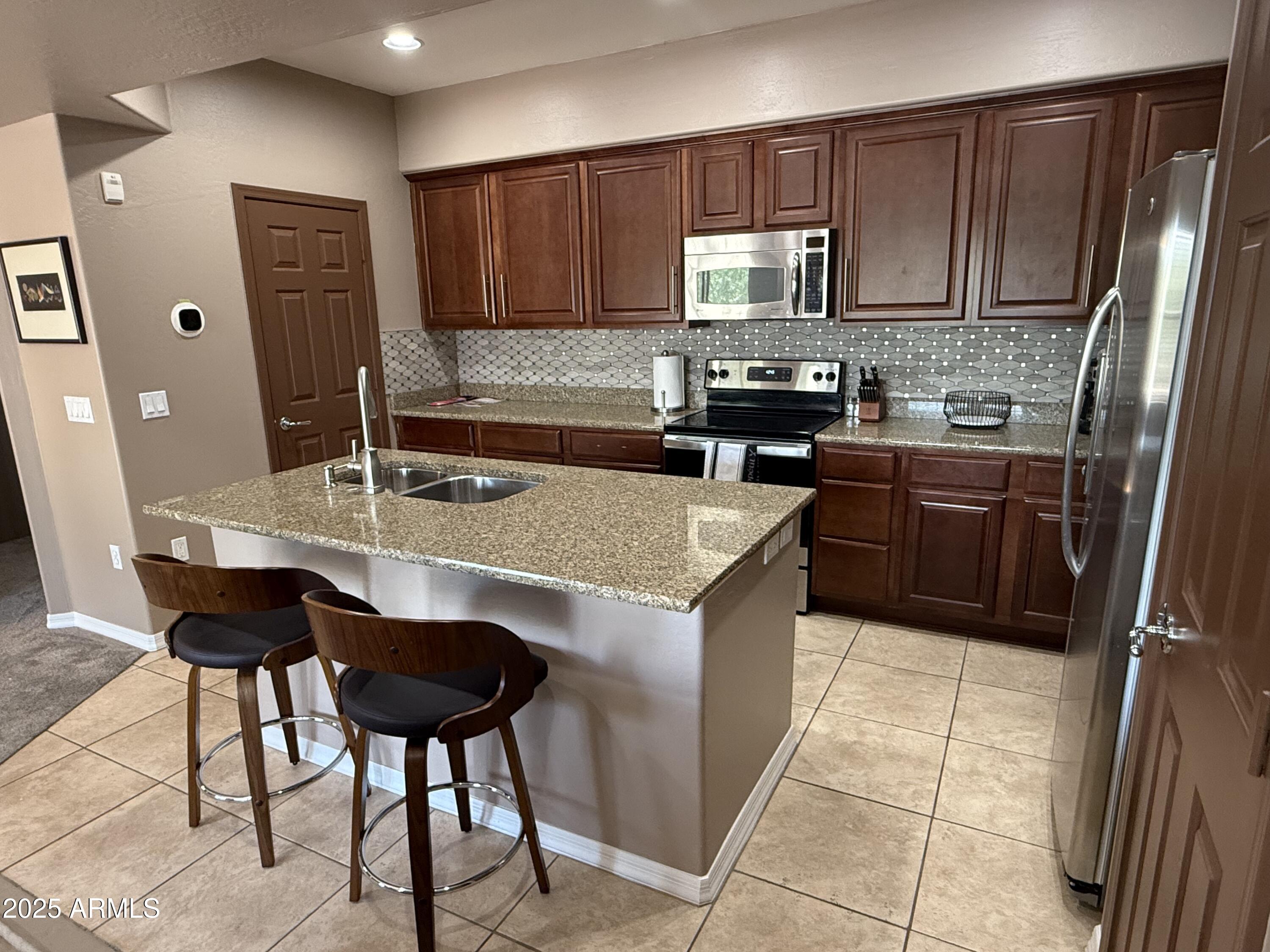 3935 East Rough Rider Road, Unit 1014 Phoenix, AZ 85050 - Photo 6 of 40 a kitchen with a stove a sink and a refrigerator