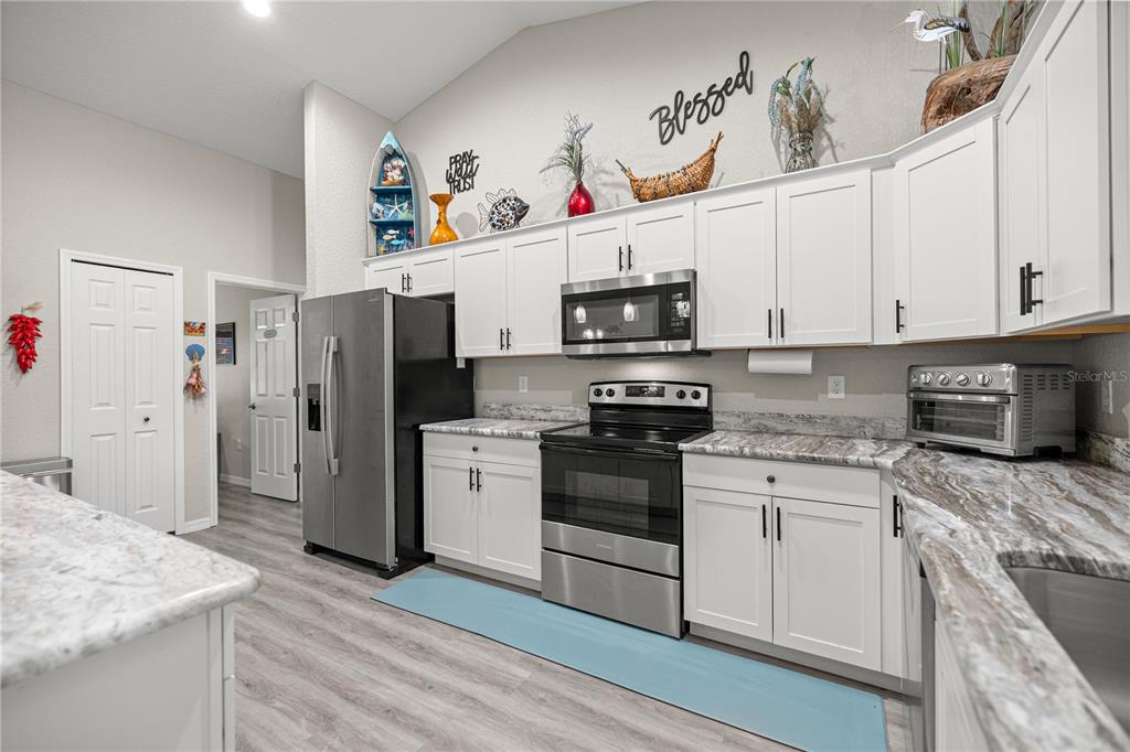 9239 Southwest 197th Circle Dunnellon, FL 34432 - Photo 14 of 57 a kitchen with stainless steel appliances granite countertop a refrigerator sink and white cabinets