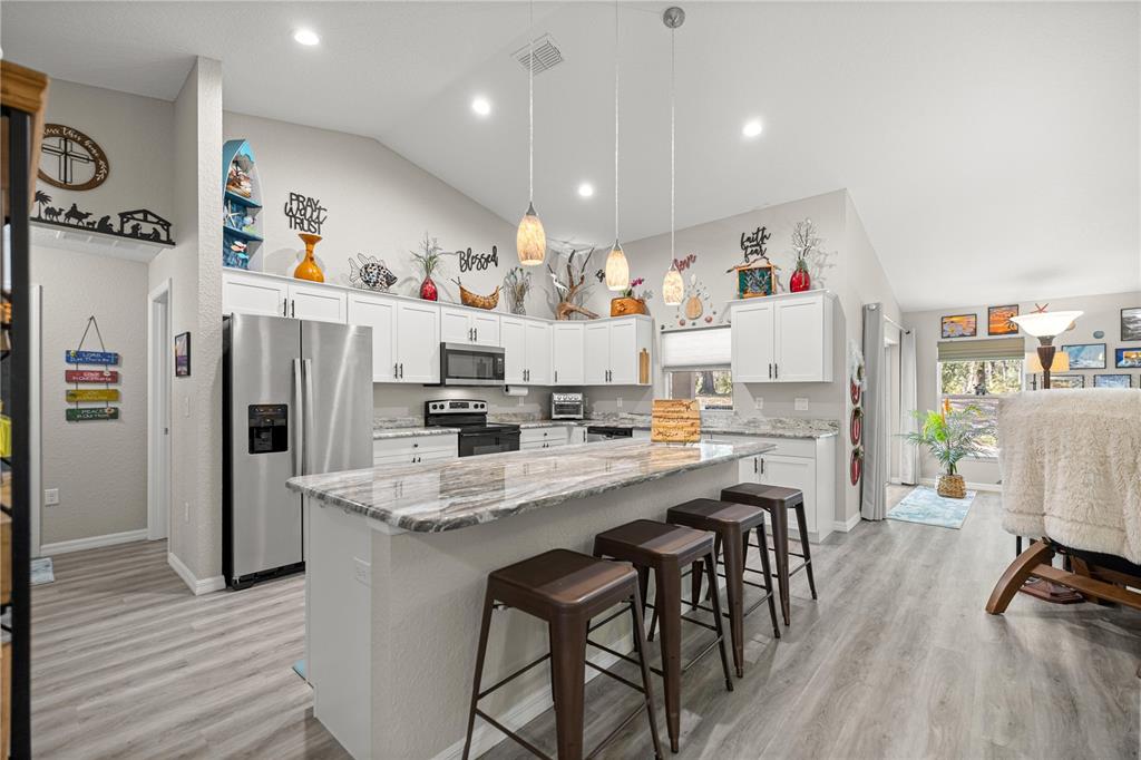 9239 Southwest 197th Circle Dunnellon, FL 34432 - Photo 9 of 57 a kitchen with stainless steel appliances kitchen island granite countertop a refrigerator and a stove top oven