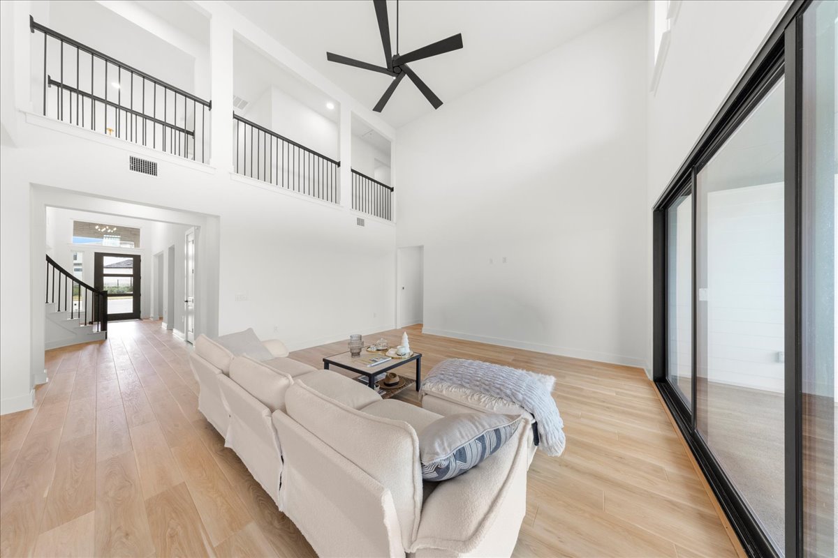 8700 Olmsted Way Austin, TX 78744 - Photo 16 of 40 Living room with light wood finished floors, a towering ceiling, stairway, and a ceiling fan