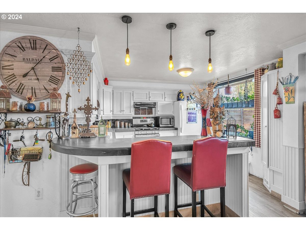 26901 Northwest St Helens Road Scappoose, OR 97056 - Photo 29 of 43 a kitchen with stainless steel appliances kitchen island granite countertop a table chairs and a wooden floors