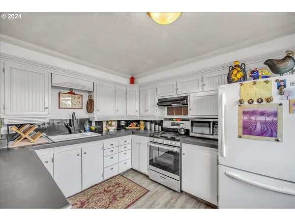 a kitchen with granite countertop a stove a sink and a white cabinets