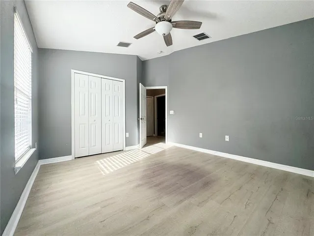 an empty room with fan and windows