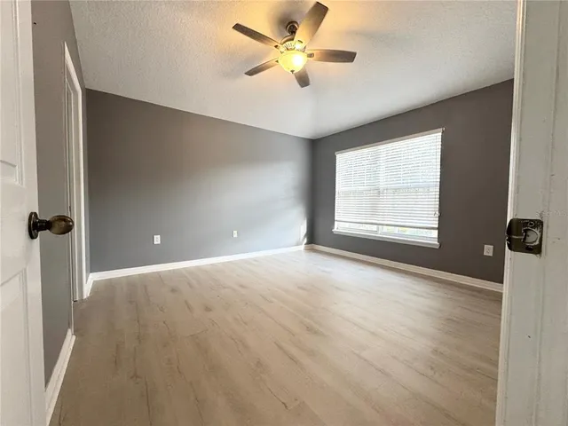 an empty room with windows and fan